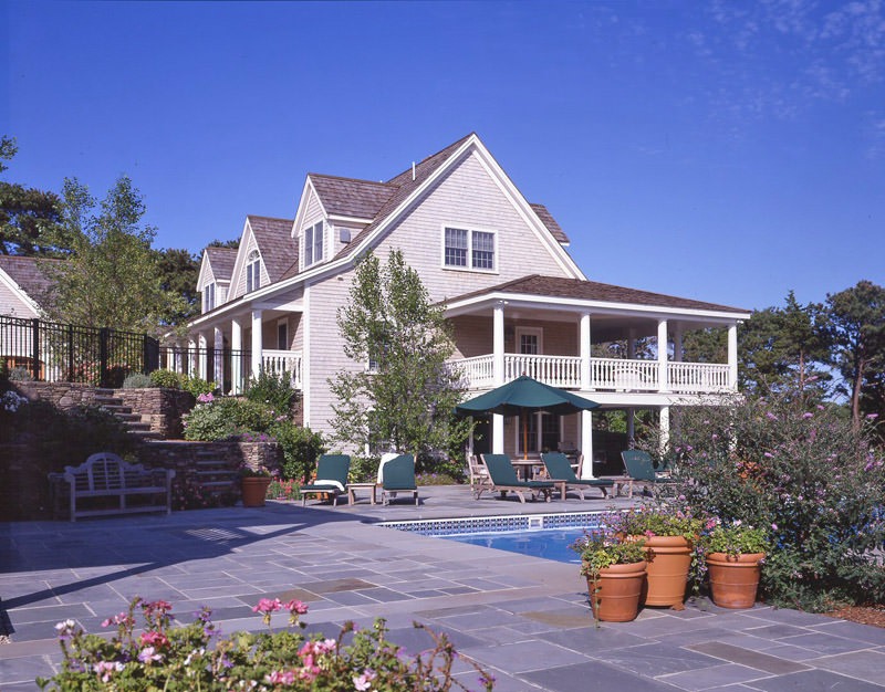 cape cod house with pool and wraparound porch