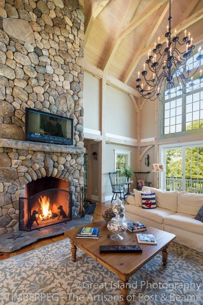 Living room with stone fireplace and television sitting on mantle, above roaring fire.