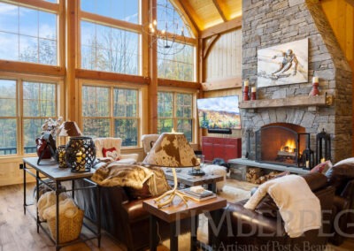 Ludlow VT T01058 great room, featuring stone fireplace and window wall looking out to woods