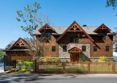 Lake Winnipesaukee, NH Retreat front exterior view featuring four dormers with decorative trusses, stone and shingle siding