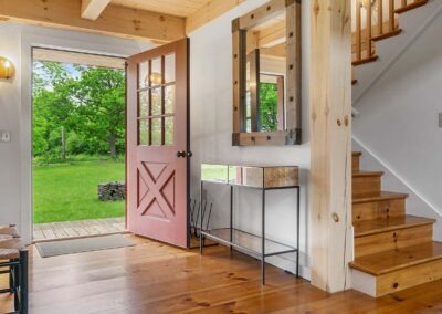 The entryway of an Old Chatham Barn Home with stairs and a door.