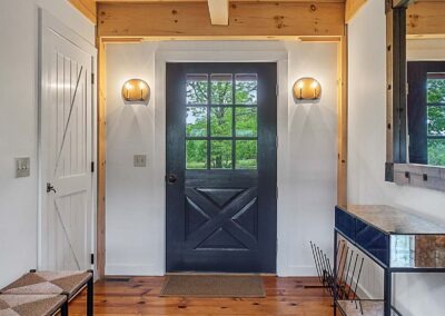 A hallway with a black door in an Old Chatham Barn Home.