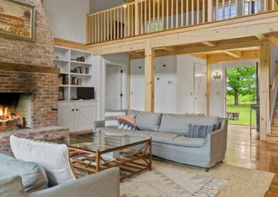 Old Chatham Barn Home with a living room featuring a fireplace and stairs.
