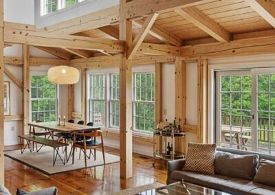 A rustic living room with wood beams and a fireplace, located in an Old Chatham Barn Home.
