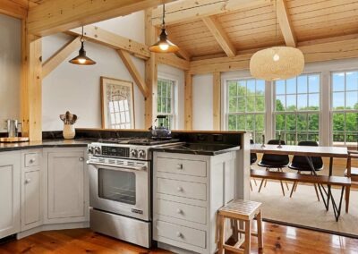 A kitchen in an Old Chatham Barn Home with wood beams and a stove.