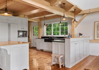 Old Chatham Barn Home featuring a white kitchen with wooden beams and wood floors.