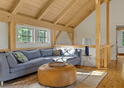 An Old Chatham Barn Home featuring wood beams and a couch in the living room.