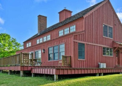 Barn style home with a deck on a green field.