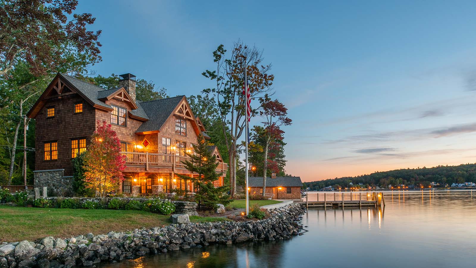 Exterior view of the back of a timber framed waterfront retreat sitting on the shore of Lake Winnipesaukee.